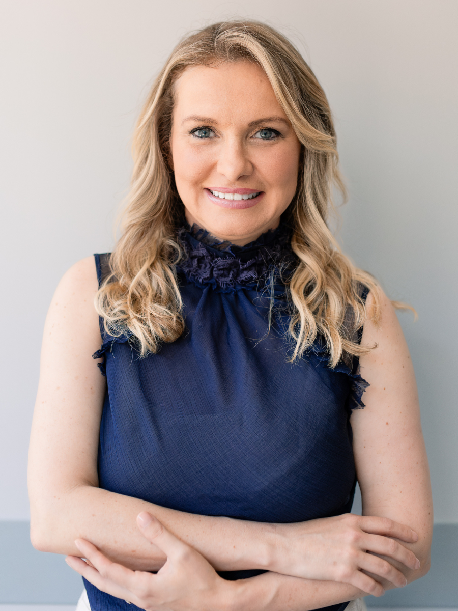 Ms. Lara de Luca, a blonde, smiling woman in a blue sleeveless top